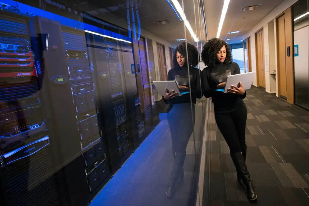 A woman using a laptop near servers.