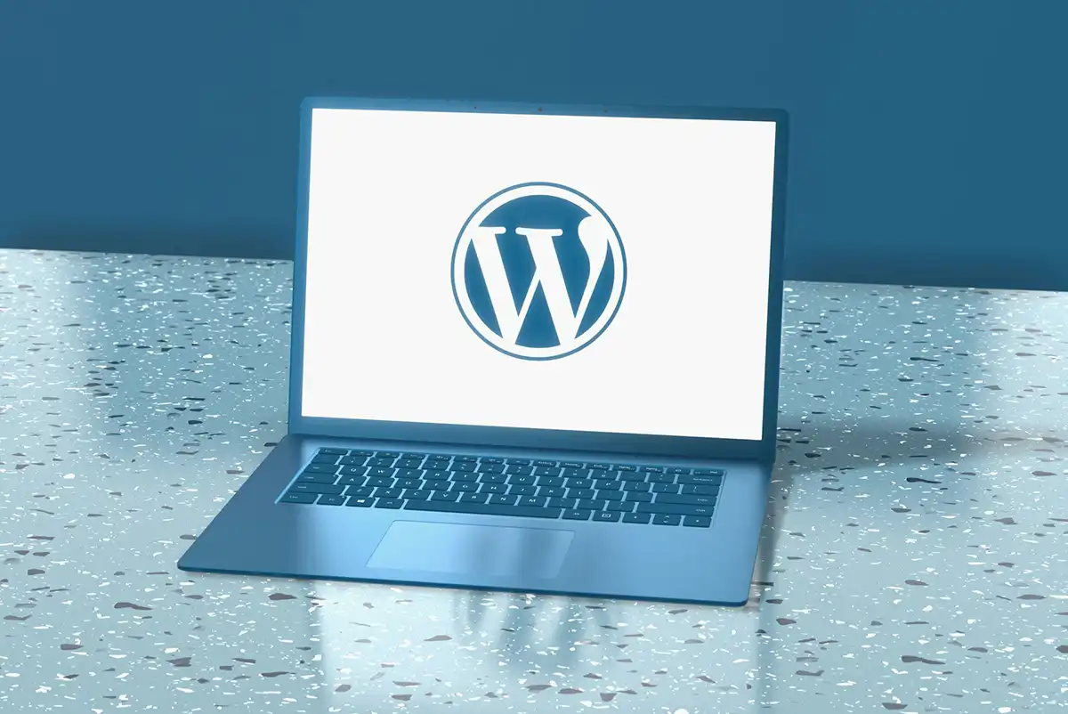 A blue laptop displaying the WordPress logo on a speckled blue surface